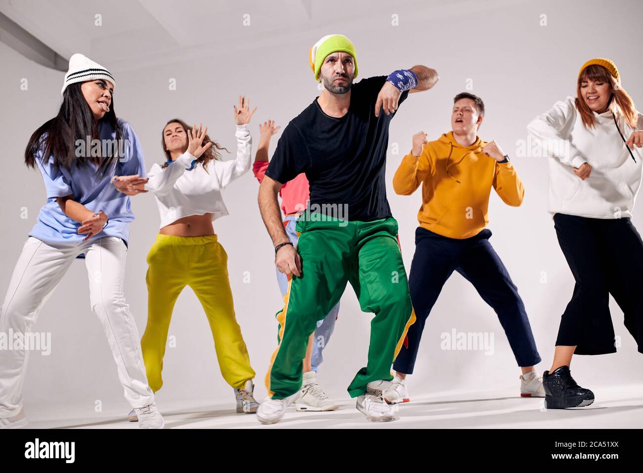 Delighted bright unshaven man wearing sportive outfit, having yellow cap  and banding bandana on wrist, performing hip hop dance together with  professi Stock Photo - Alamy