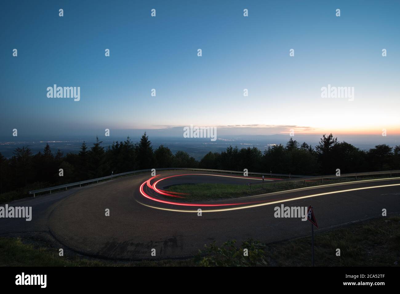light trails at evening from cars in a curve in germany. Stock Photo