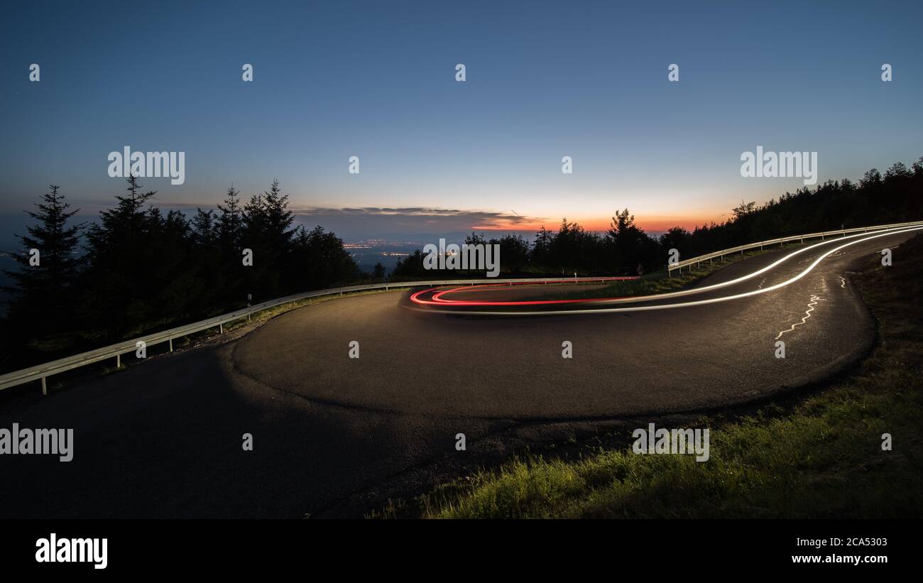 light trails at evening from cars in a curve in germany. Stock Photo