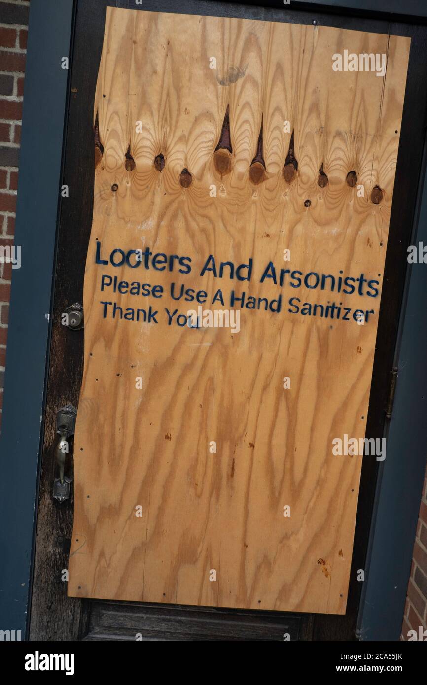Humorous sign, 'Looters and Arsonists Please use a hand sanitizer' on a store entrance door after looting and rioting in New York City, USA Stock Photo