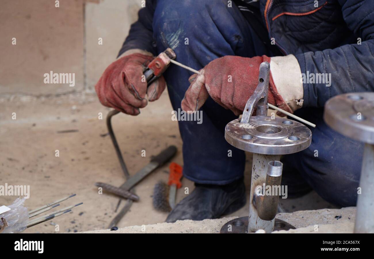Close-up welder working with electrode at semi-automatic arc welding in manufacture production plant Stock Photo