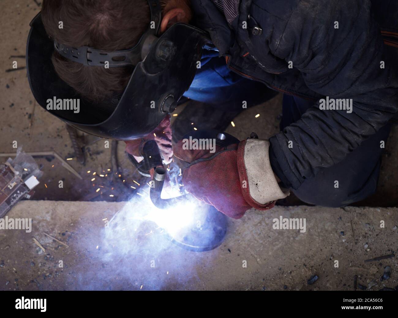 Close-up welder working with electrode at semi-automatic arc welding in manufacture production plant.Bright sparks from welding Stock Photo