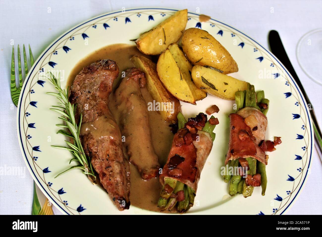 grilled lamb fillet with beans wrapped in bacon and potato wedges Stock Photo