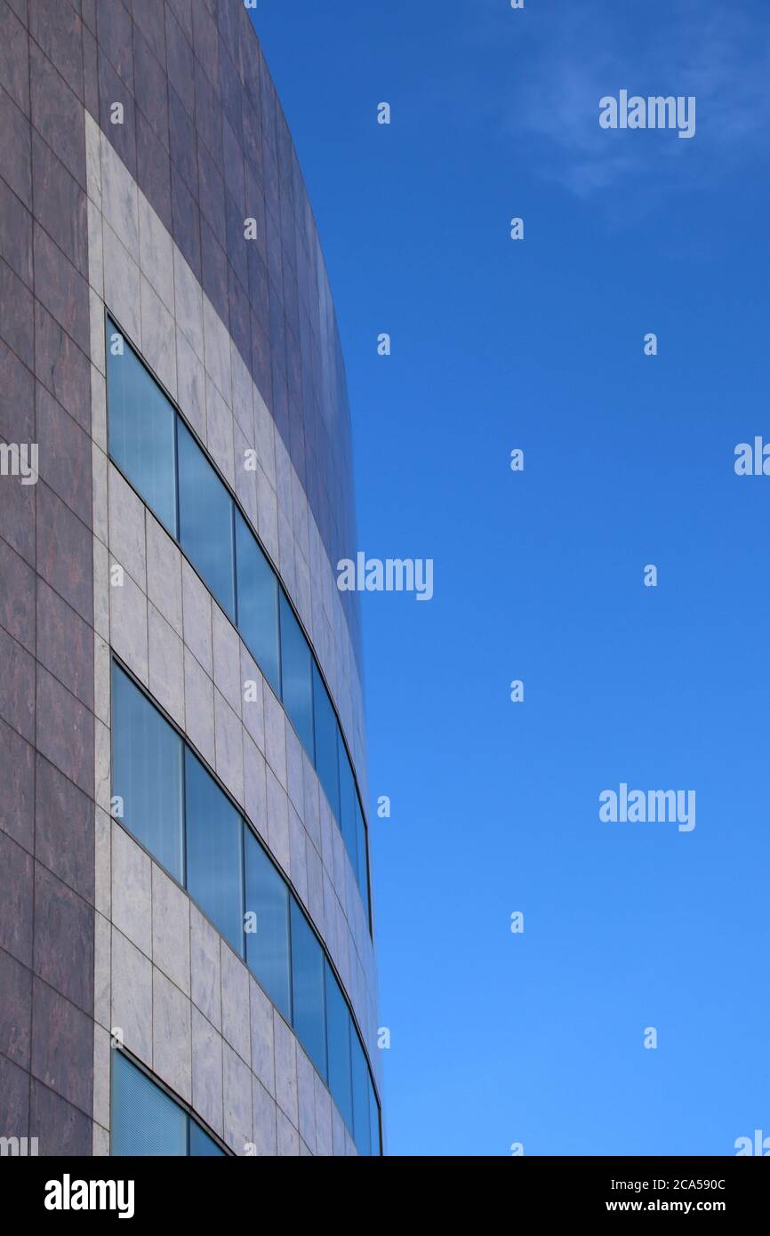 The corner of a modern curved office building against a blue sky Stock Photo