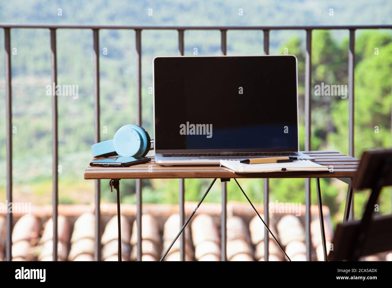 Work from home, table on the terrace of the house with portable headphones and notebook. Stock Photo