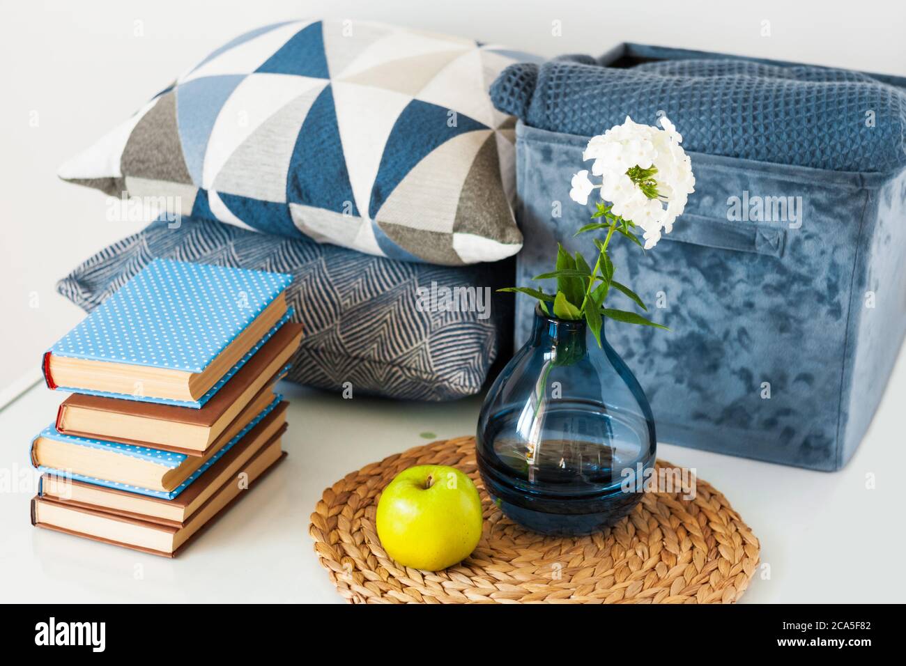 Cozy Home Interior Decor Stack Of Books Green Apple Decorative Pillows Blue Box With Plaid And Vase With White Flower On A Glass Table Distance Stock Photo Alamy