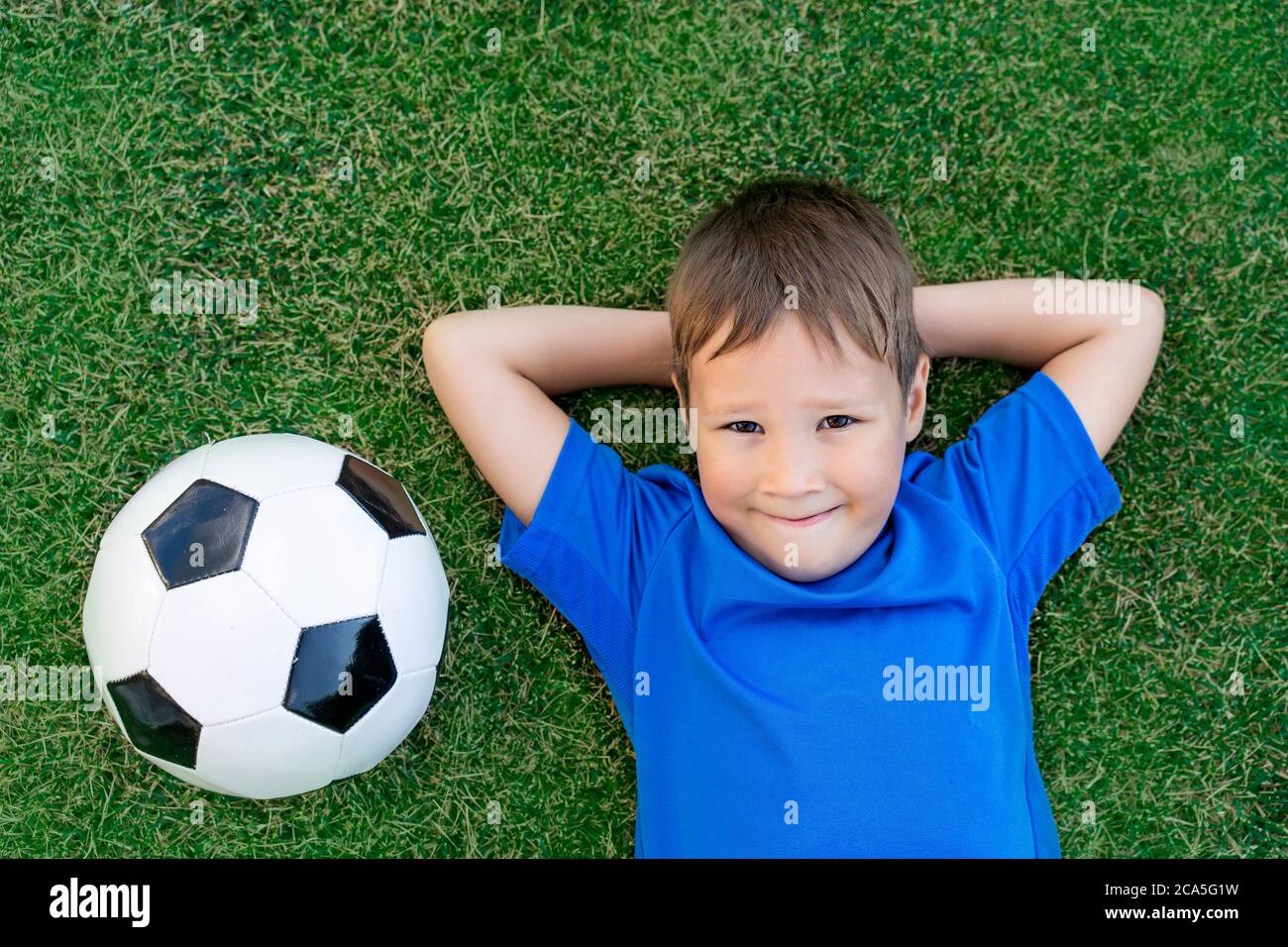 a small soccer player is lying on a soccer field with a soccer ball