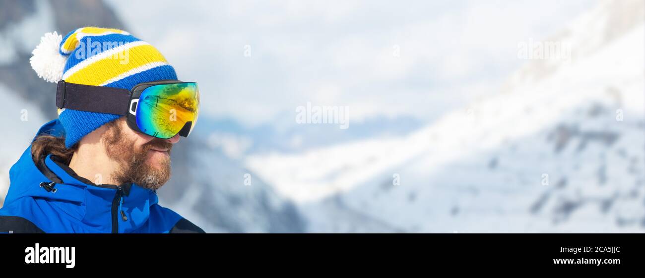 Close up portrait of man skier in hat and ski goggles mask looking at mountain range Col Gallina Cortina d'Ampezzo Dolomites Stock Photo