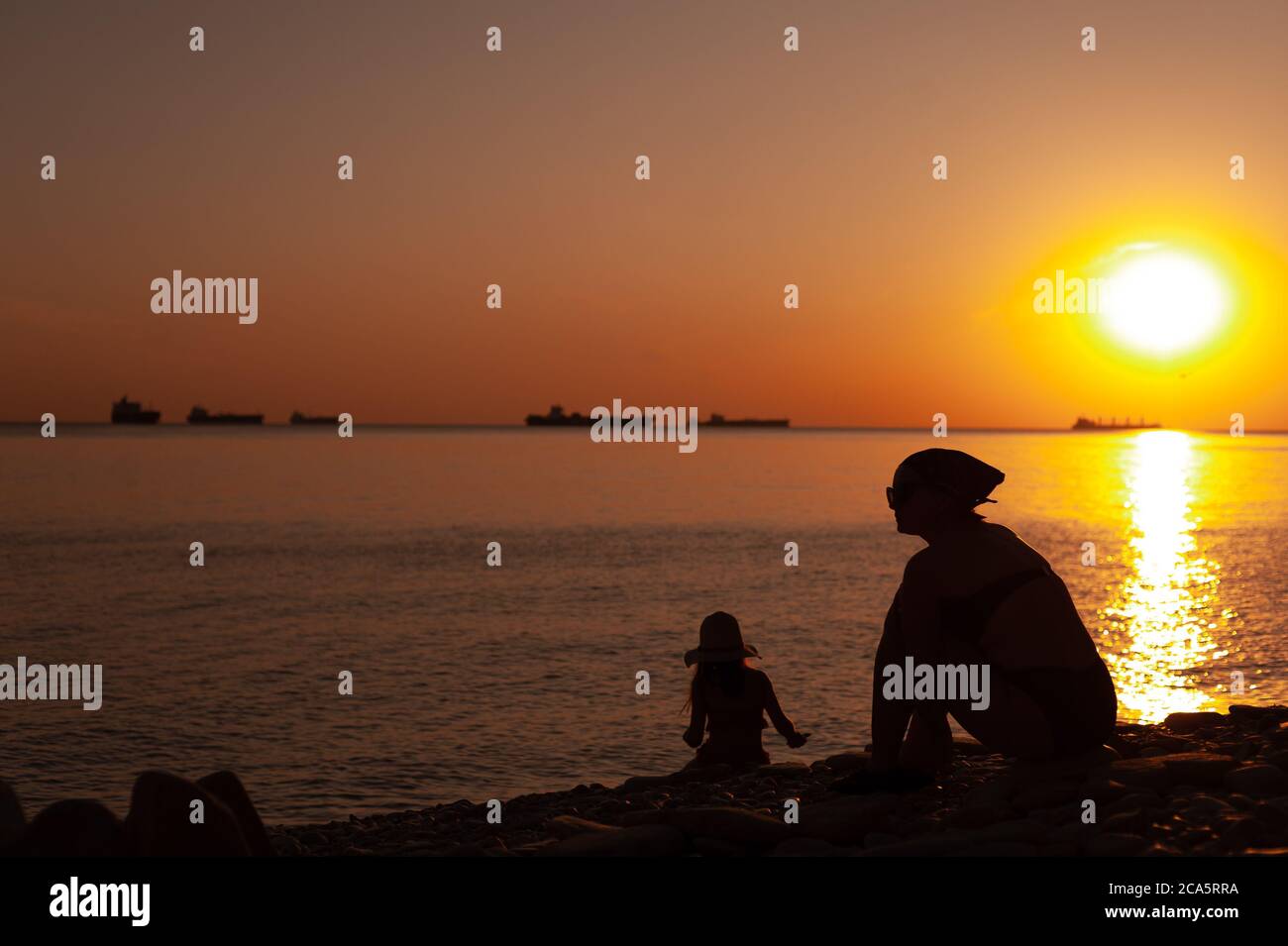 A man standing on a beach in front of a sunset Stock Photo