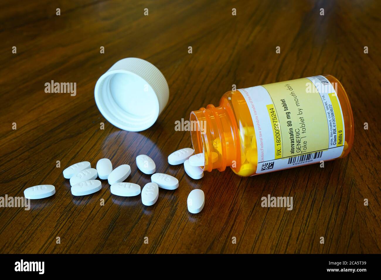 A spilled bottle of cholesterol medication on wood table Stock Photo