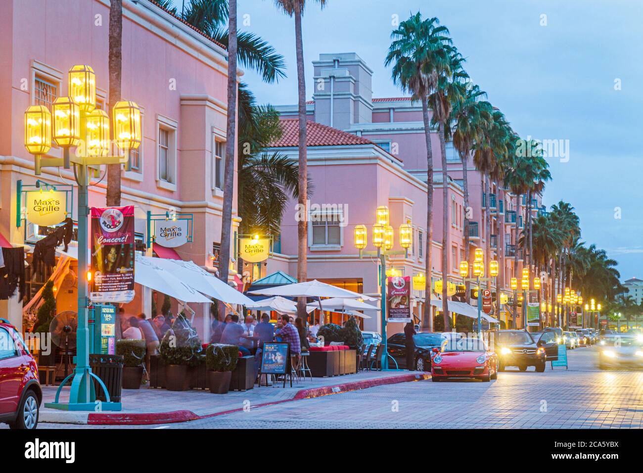 Boca Raton Florida,Mizner Park Plaza Real,shopping shops stores al fresco,Max's Grille restaurant lampposts evening nightlife pink buildings palm tree Stock Photo