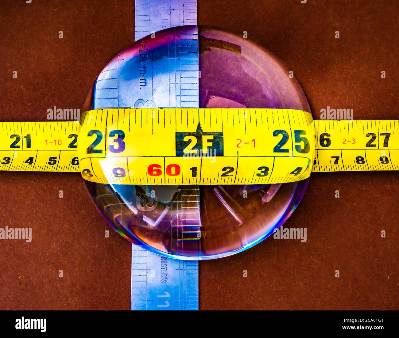 A dome magnifying glass on top of a steel rule and a tape measure