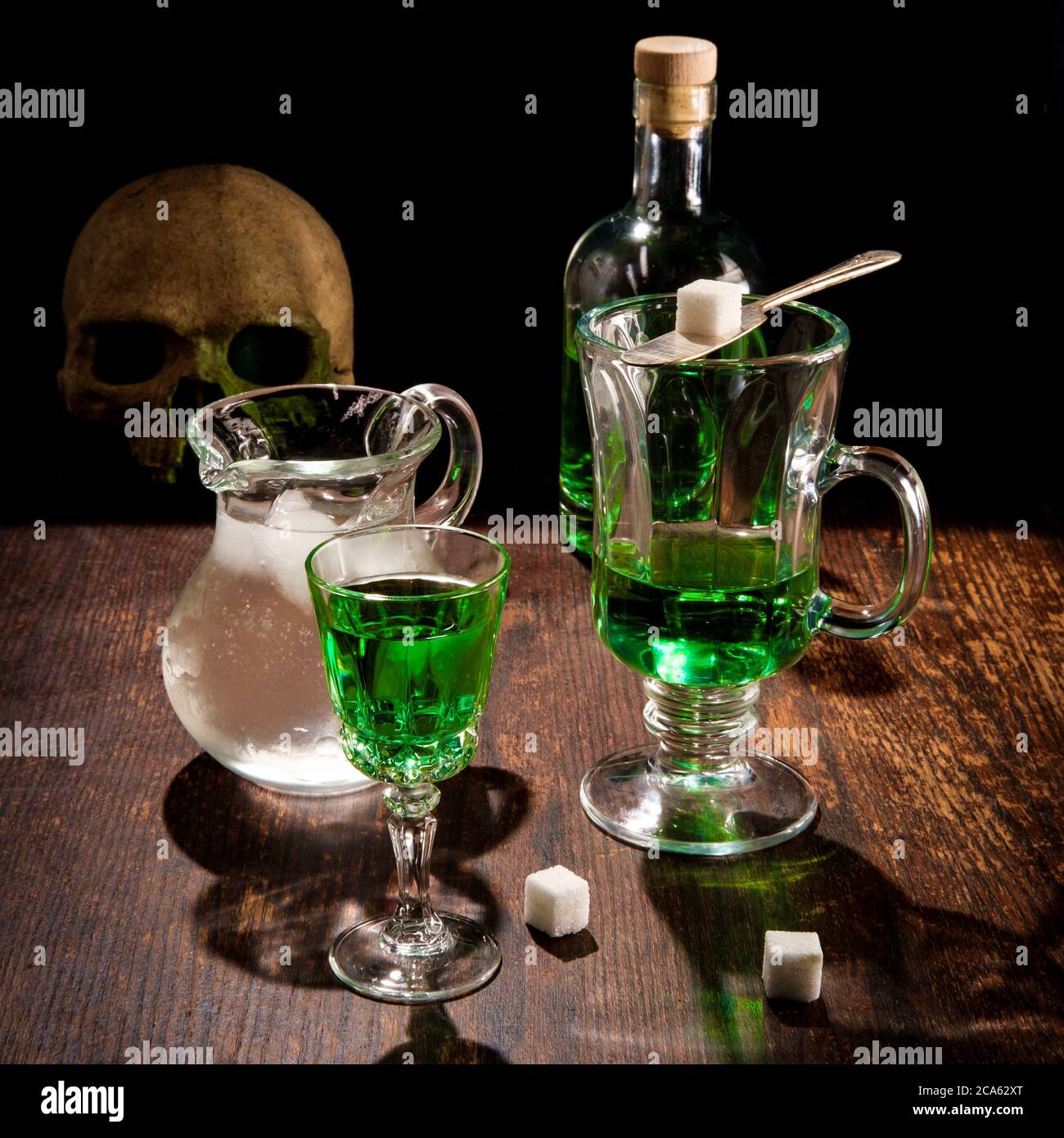 Green absinthe liquor in glass with ice water to pour over sugar cube
