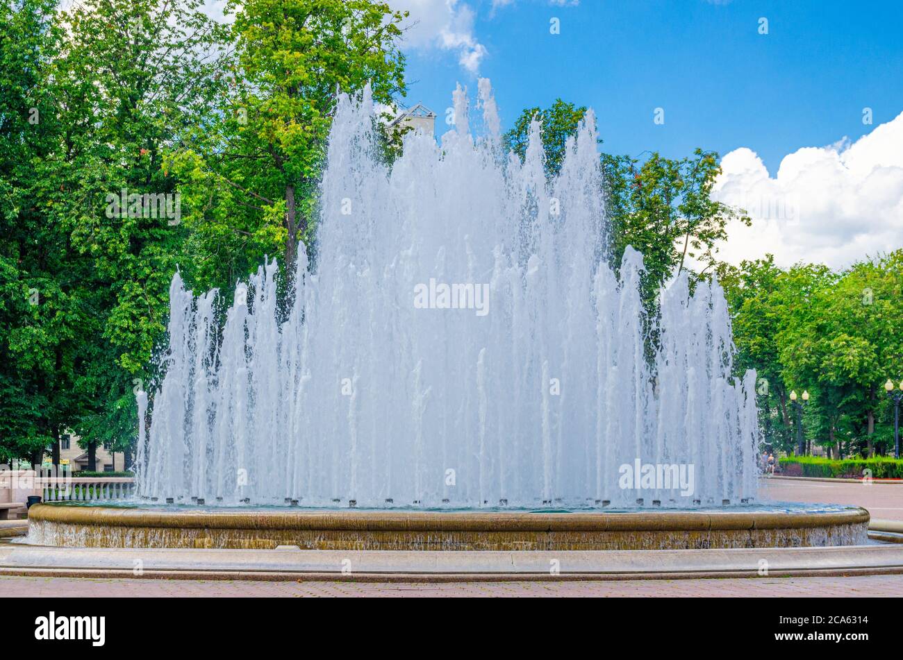 Water fountain near Opera and Ballet Theatre building in park in Trinity Hill district of Minsk city historical centre, blue sky white clouds in sunny summer day, Republic of Belarus Stock Photo