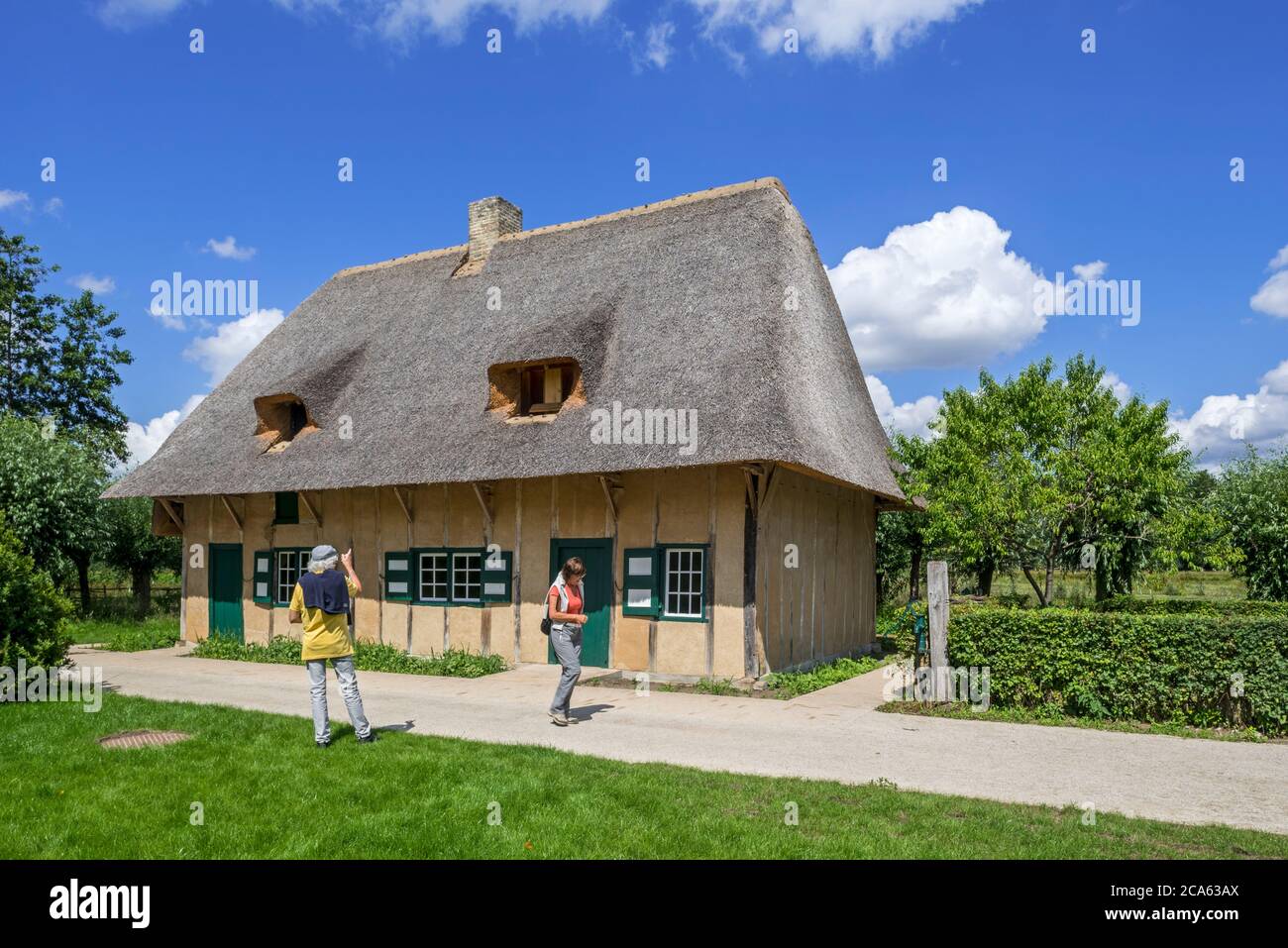 Tourists visiting 19th century rural house Oostvleteren with thatched roof at the open air museum Bokrijk, Limburg, Flanders, Belgium Stock Photo