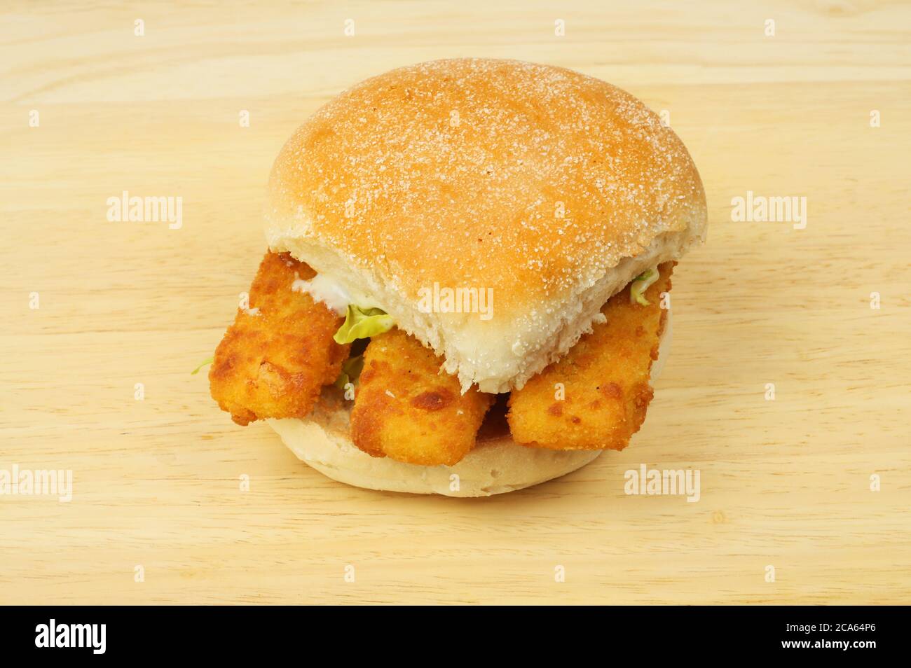 Fish fingers in a bread roll on a wooden chopping board Stock Photo