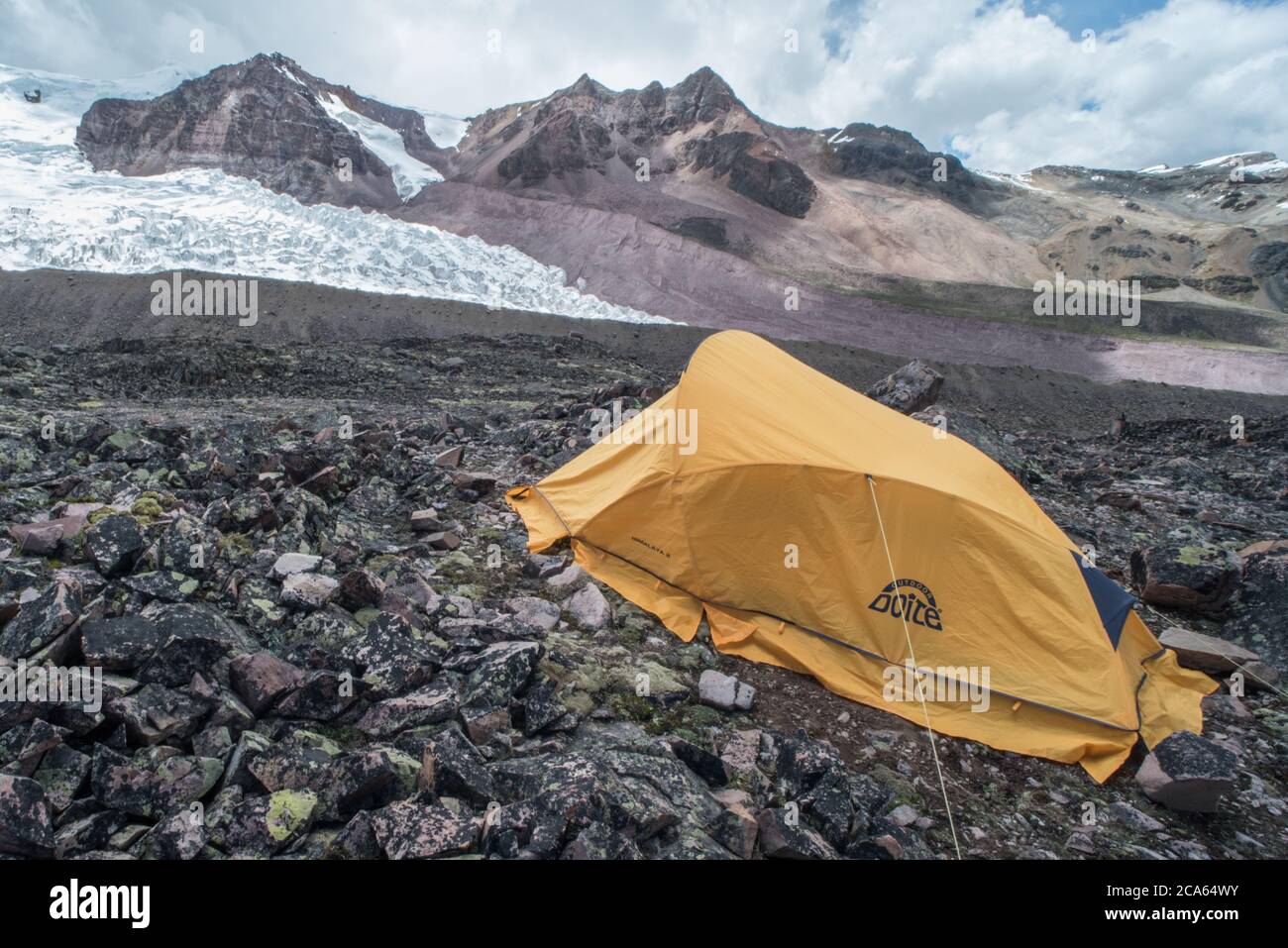 A single yellow tent of researchers camping high in the Cordillera Vilcanota next to a Peruvian glacier in the Andes mountains. Stock Photo