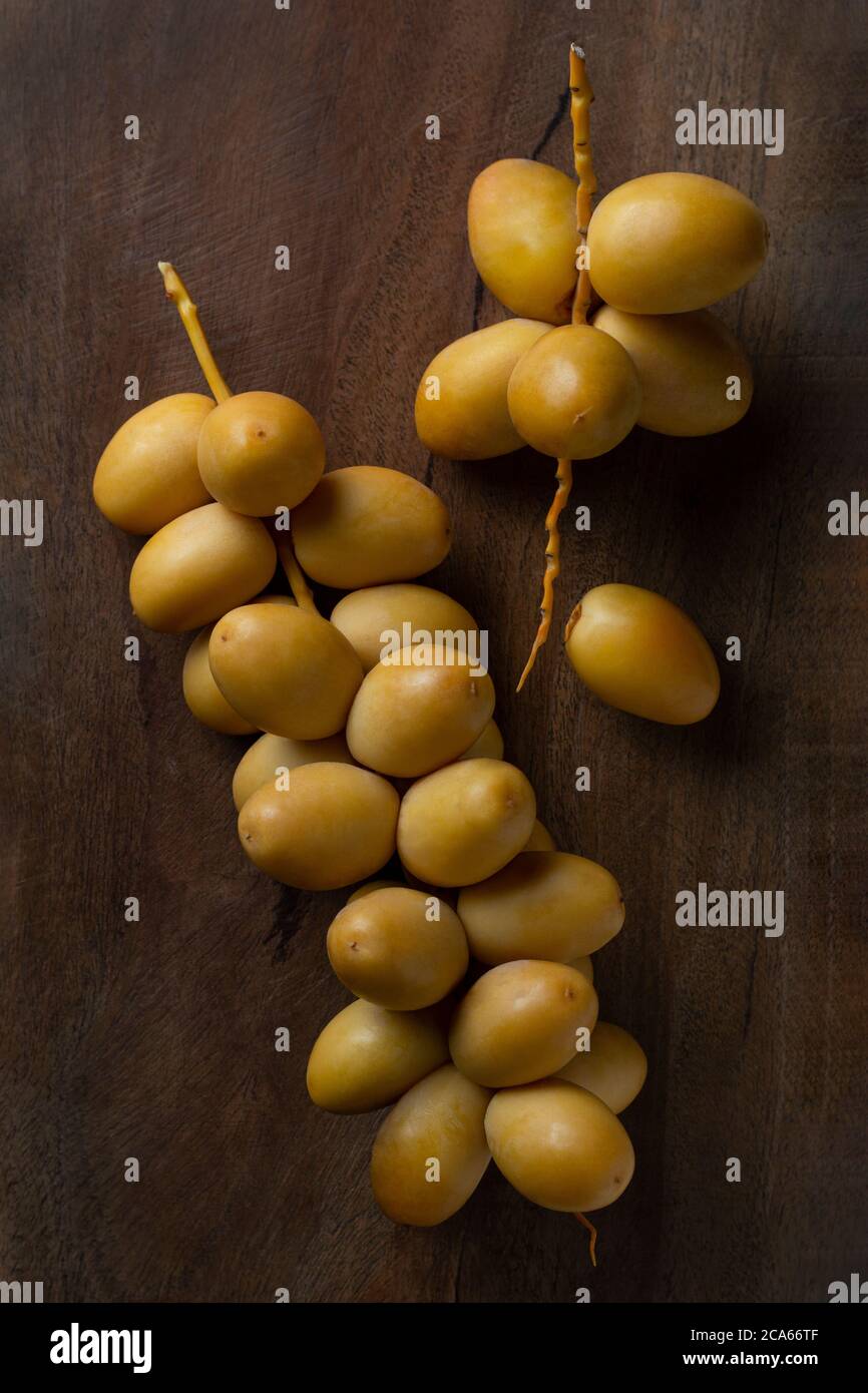 fresh yellow dates isolate on wooden background Stock Photo - Alamy
