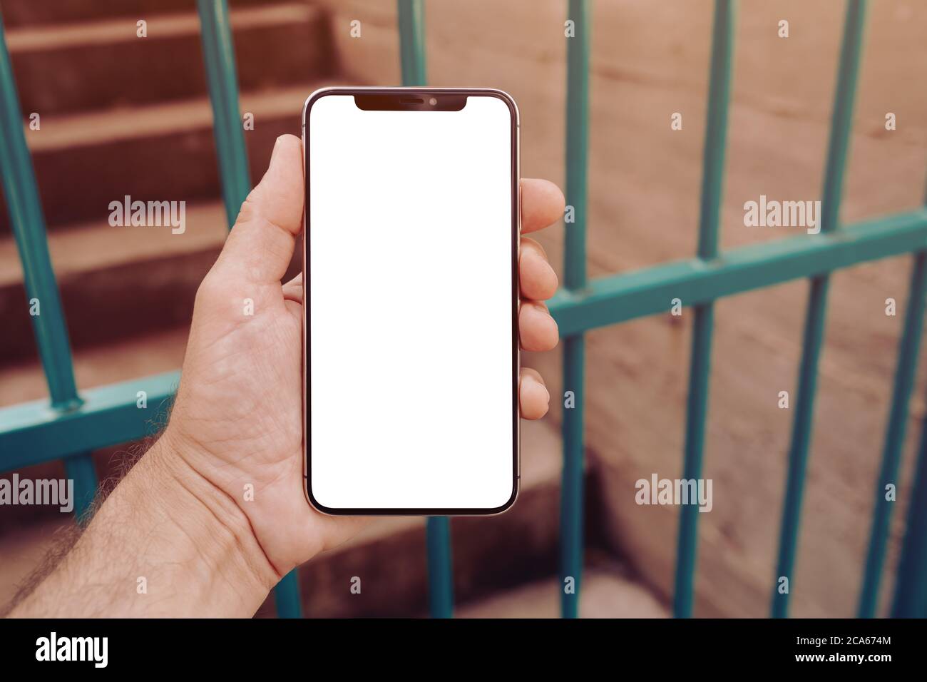 Mockup of smartphone screen on the street in urban surrounding, man holding modern smart phone with blank display as copy space Stock Photo