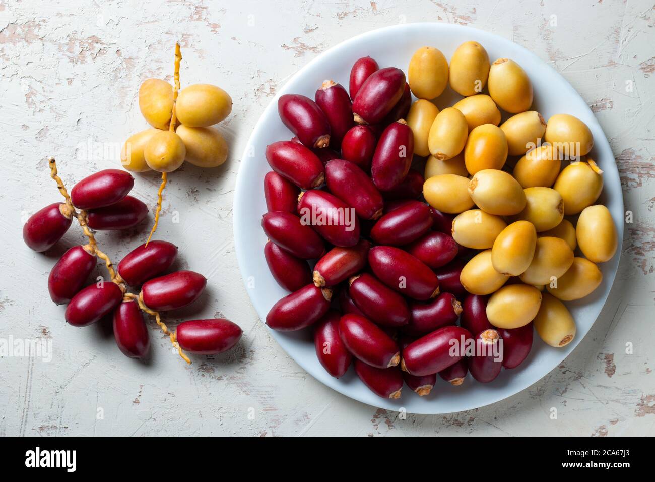 red and yellow fresh dates fruit in white plate Stock Photo