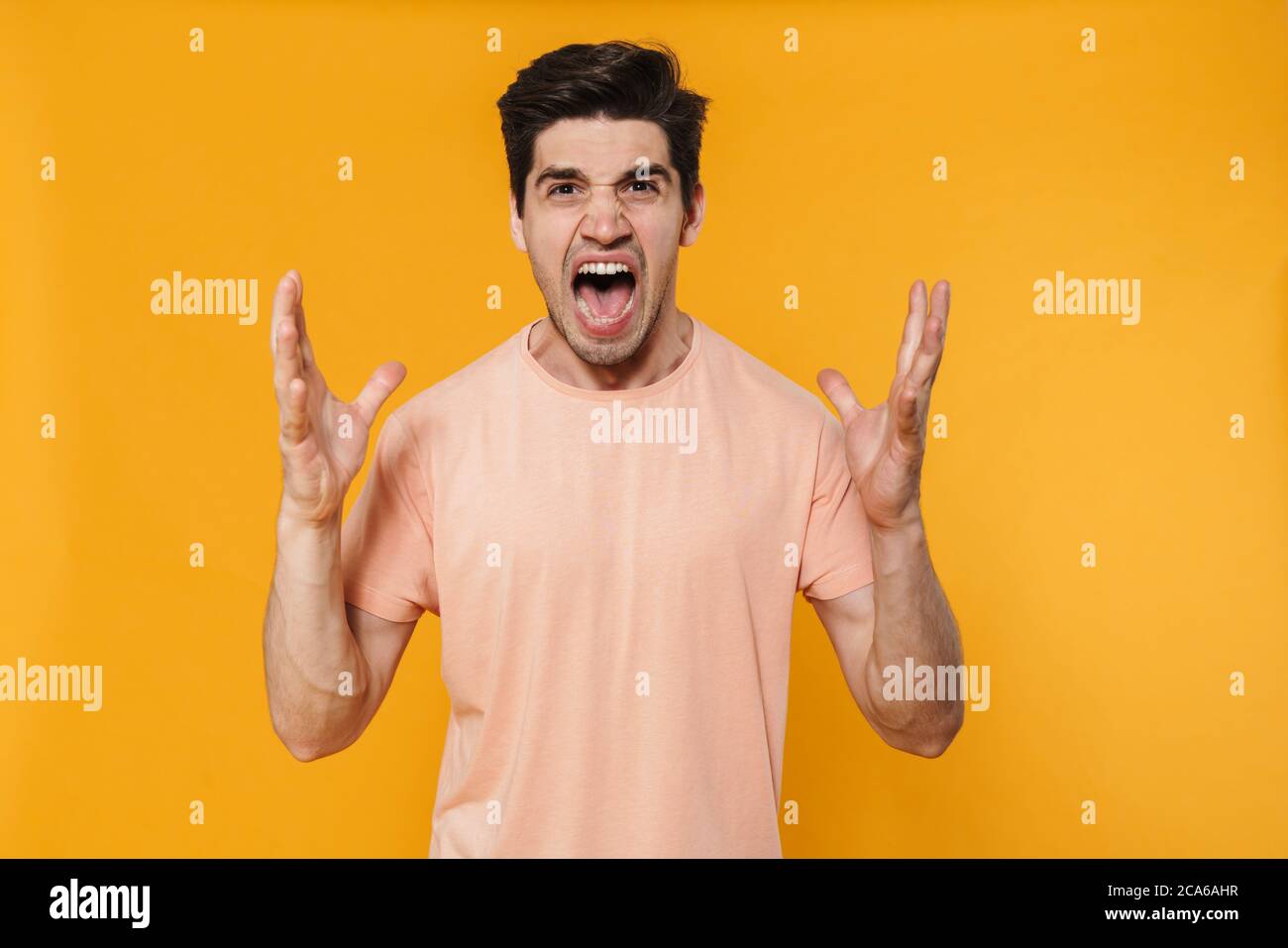 Photo of furious handsome man screaming with throwing up hands isolated