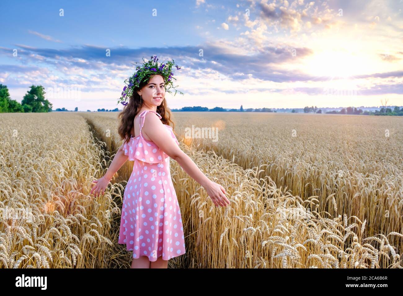 Young woman with flower wreath stands turning around and smiling Stock Photo
