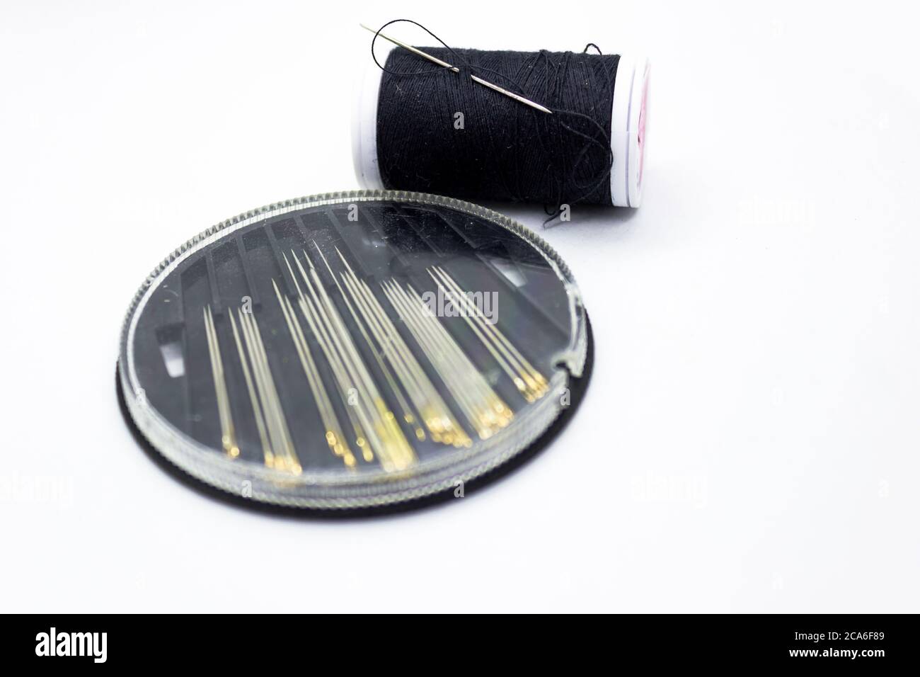 Sewing needle threader tool in use and a single black string Stock Photo -  Alamy