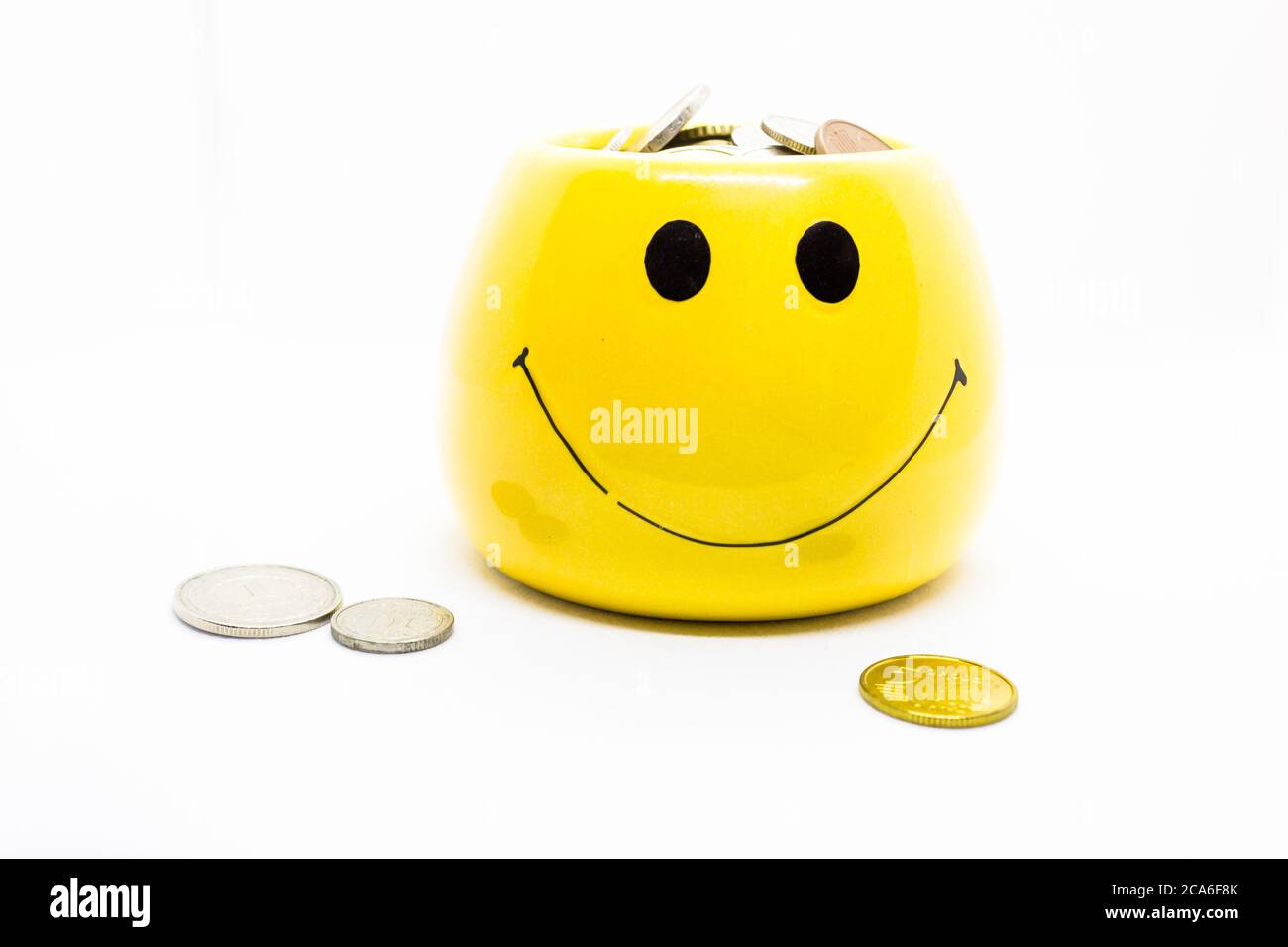 Image representing money saving and it's benefit by portraying coins in a yellow cup with smiley Stock Photo