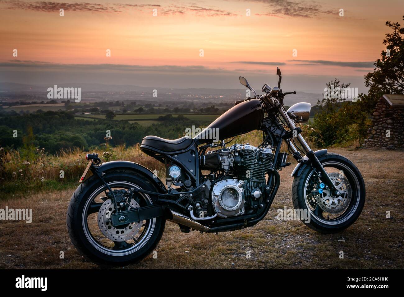 A custom made motorcycle (chopper) parked up on a quiet summer evening with the River Exe estuary in Devon in the background Stock Photo