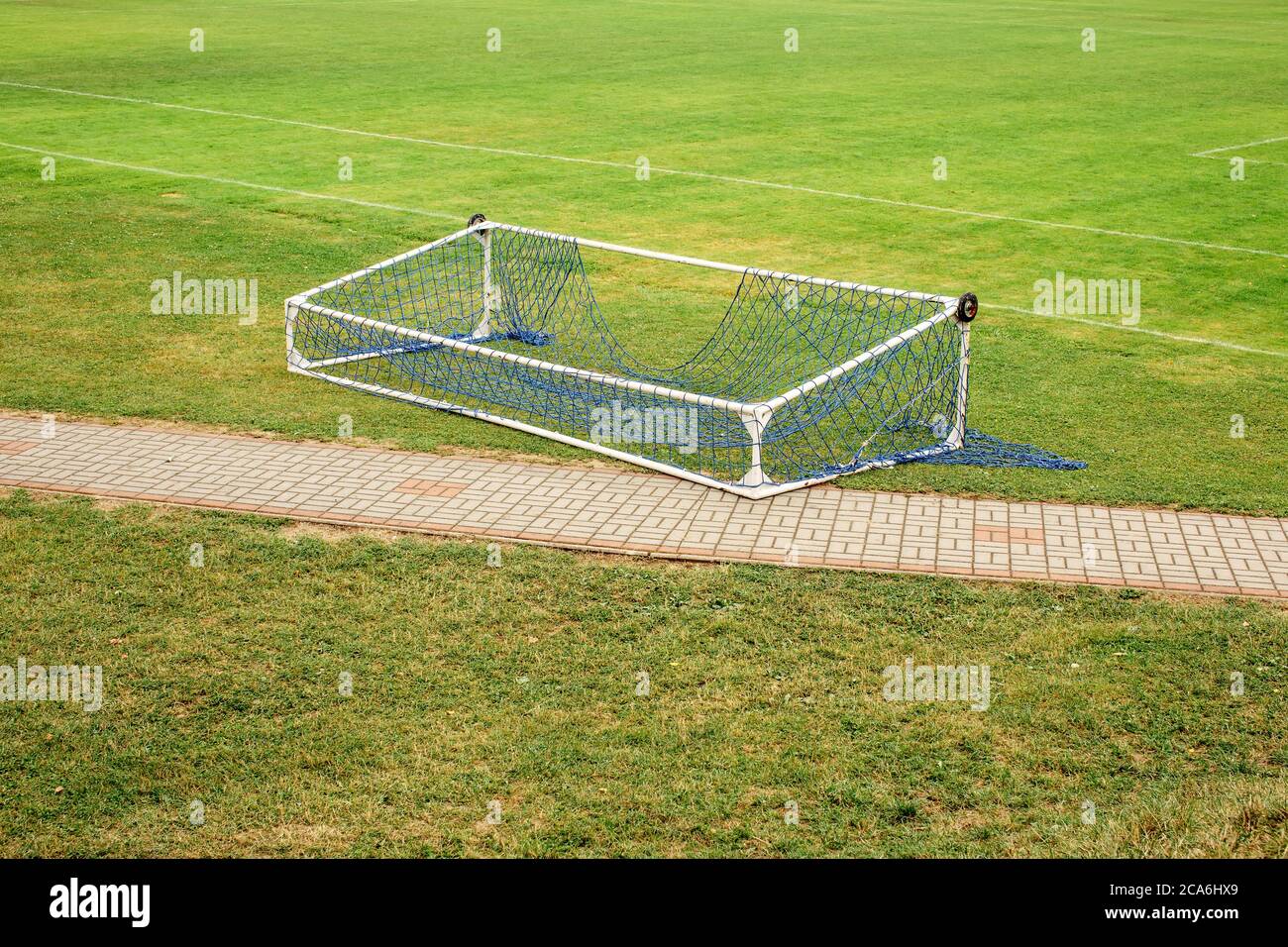 Abandoned fallen soccer football gate lying on empty green field Stock Photo