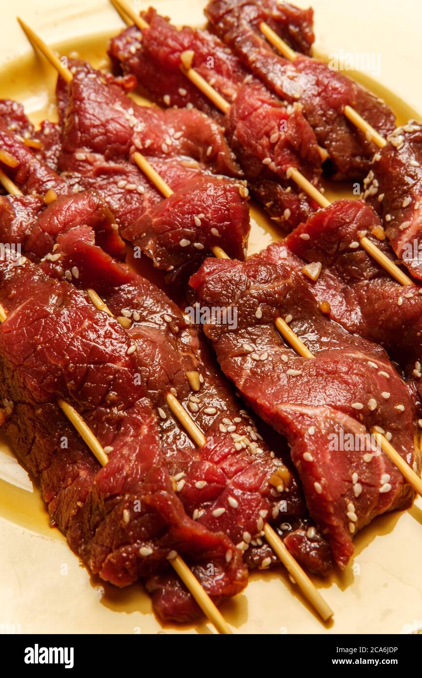 Raw marinating Korean BBQ beef Bulgogi kebab skewers with sesame seeds