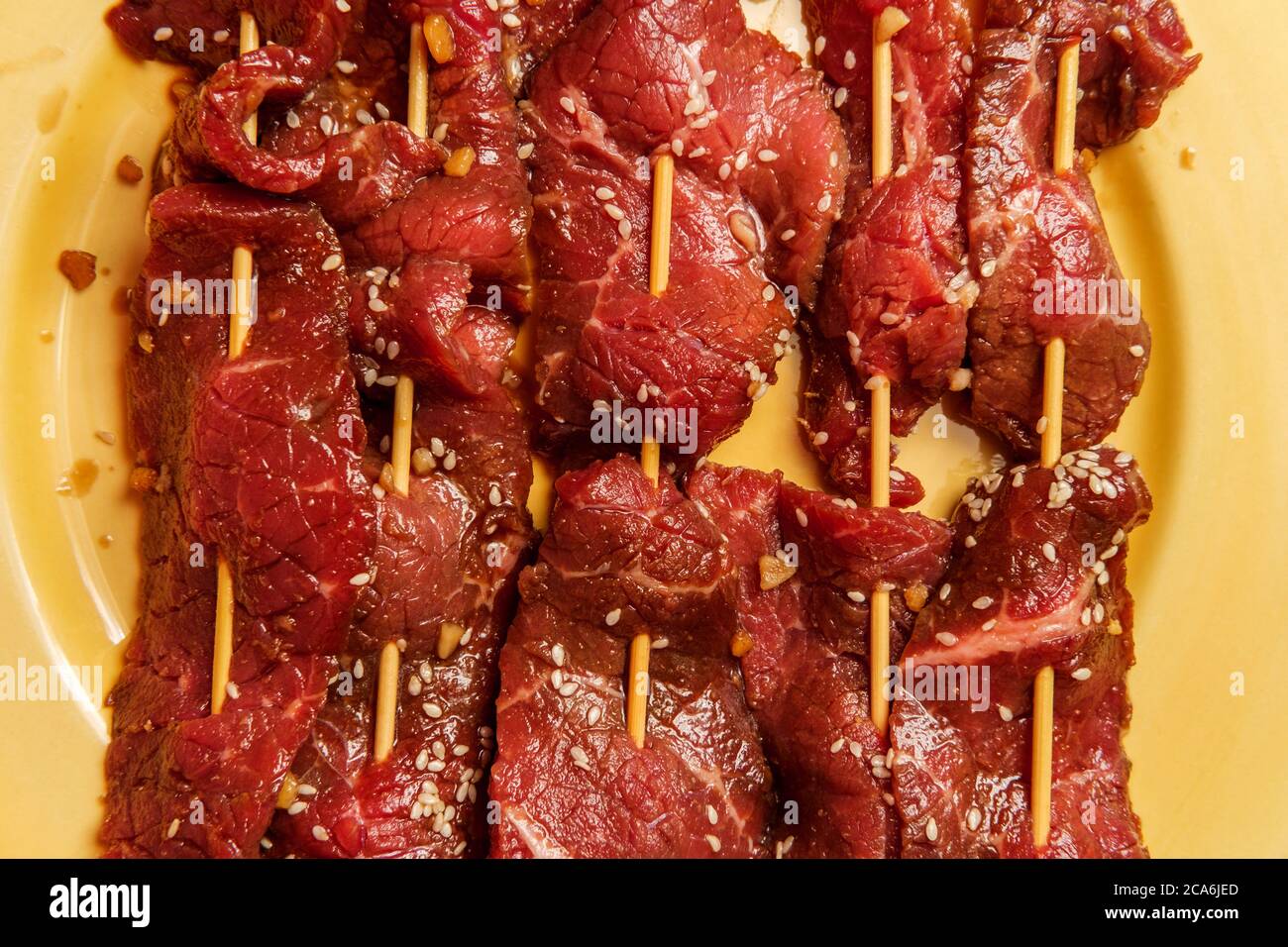 Raw marinating Korean BBQ beef Bulgogi kebab skewers with sesame seeds