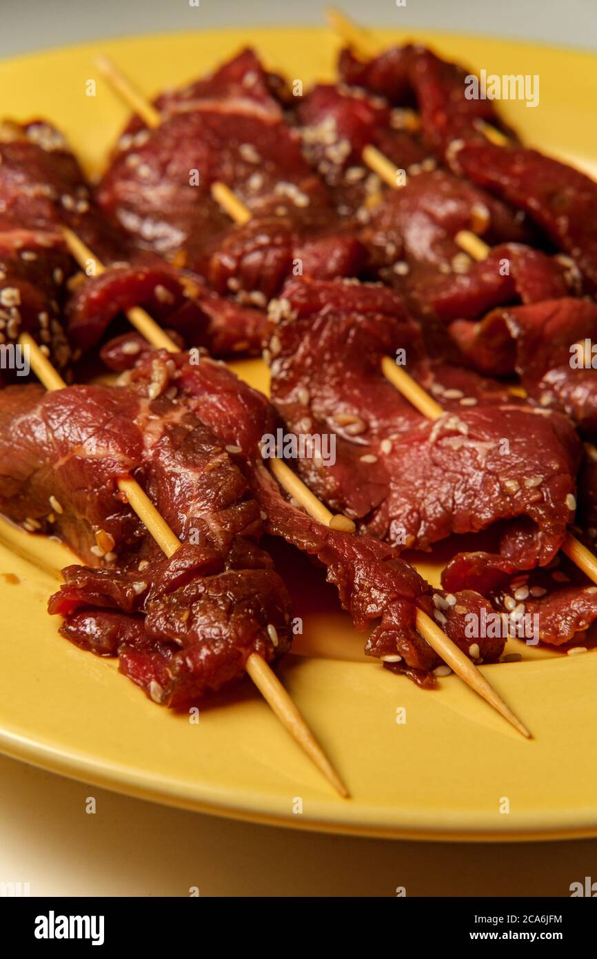 Raw marinating Korean BBQ beef Bulgogi kebab skewers with sesame seeds