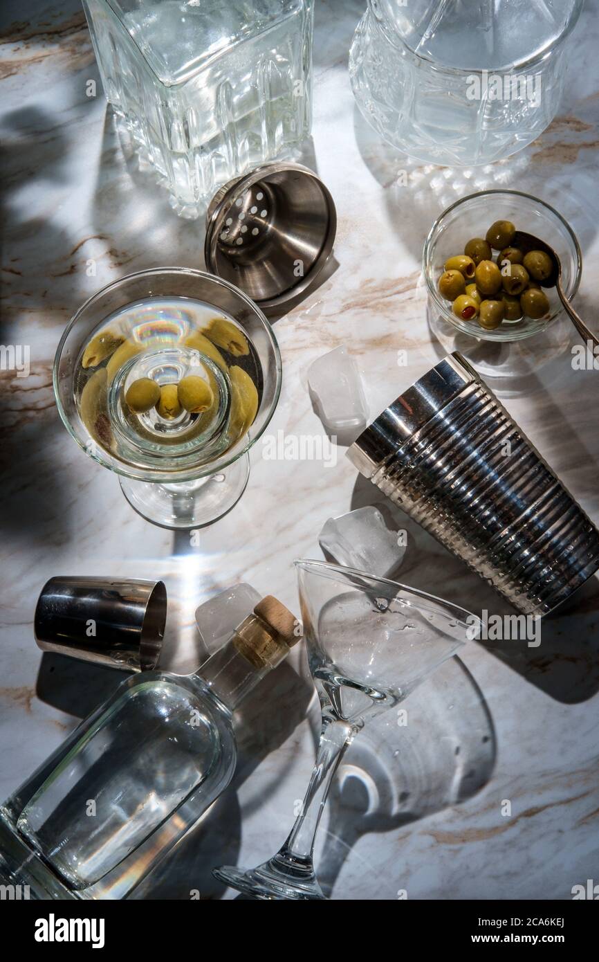 Making dirty gin martini shaken served straight up and garnished with green  olives Stock Photo - Alamy