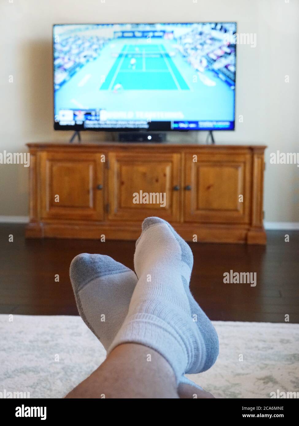 Relaxing at home by watching tennis televison with feet up Stock Photo