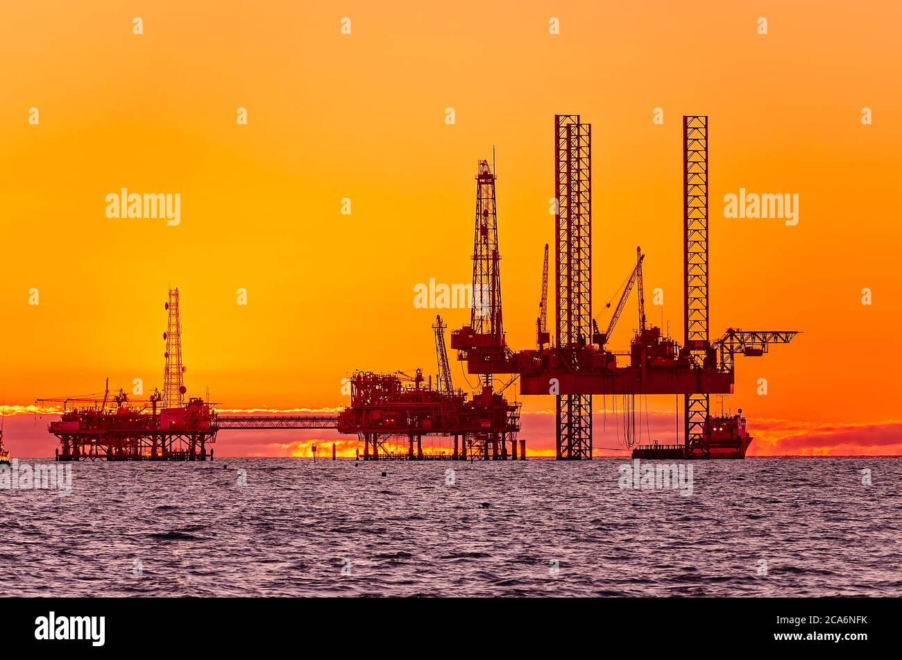 The sun rises behind a natural gas rig, April 20, 2014, in Dauphin Island, Alabama. Stock Photo