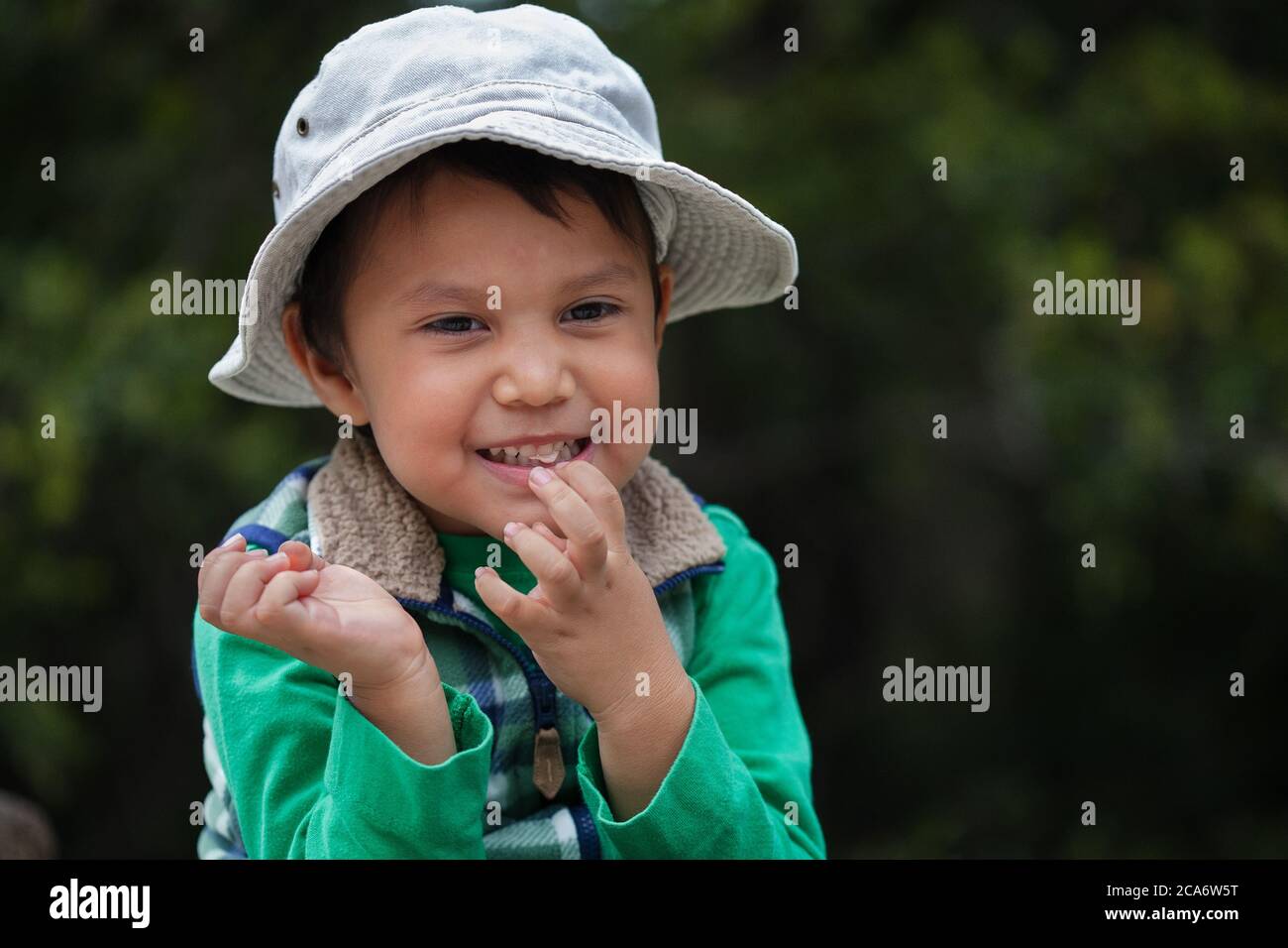 Toddler chewing gum and showing his baby teeth while outdoors on a nature trail. Stock Photo