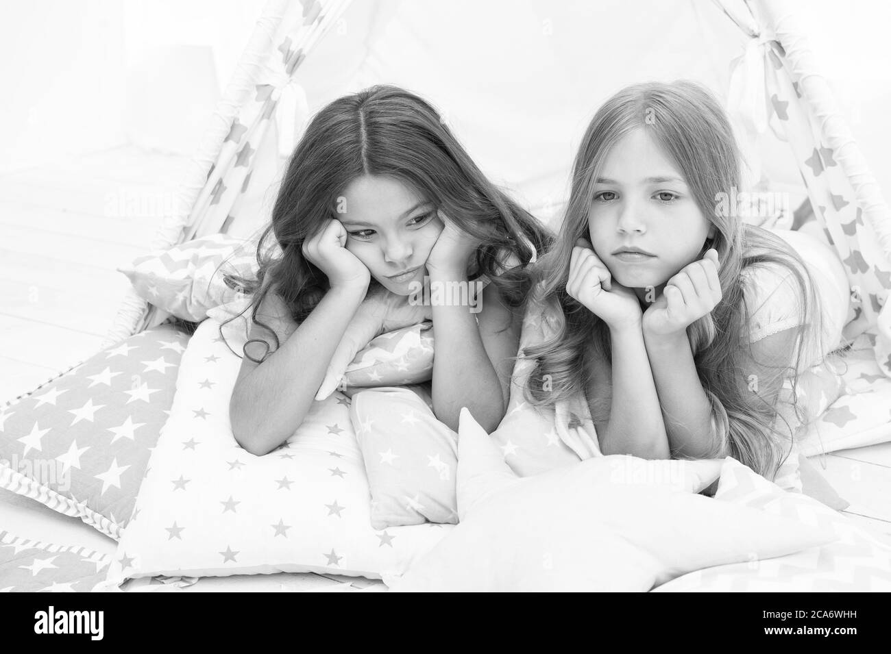 We dont want to go to bed. Unhappy children lie on bed cushions. Home accessories. Bed time routine. Bedtime. Night nursery. Good night. Resting cozy in bed. Stock Photo