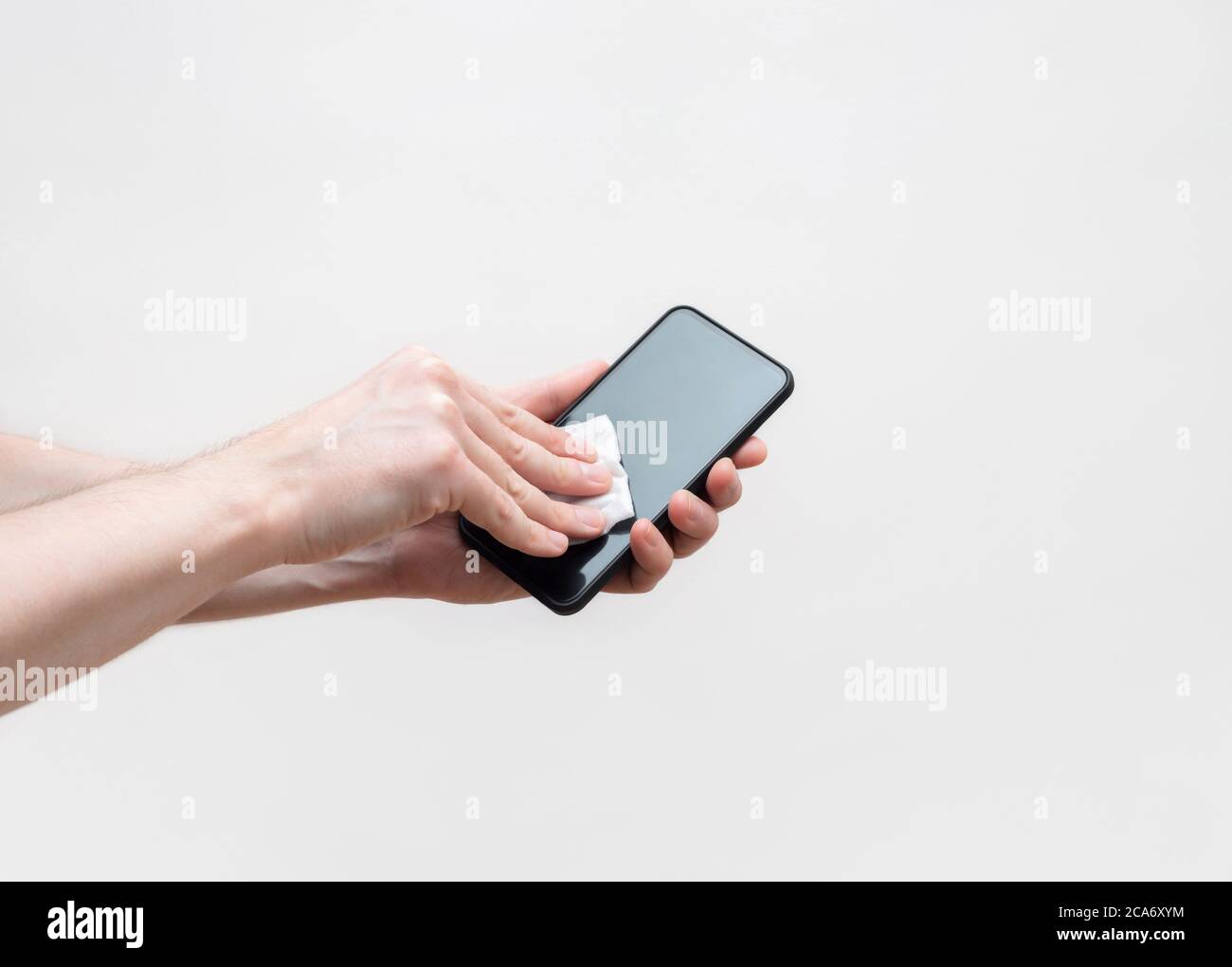 Mobile phone disinfection on a white background. Men's hands clean the phone with an antibacterial napkin. Prevention of coronavirus, covid-19. Stock Photo
