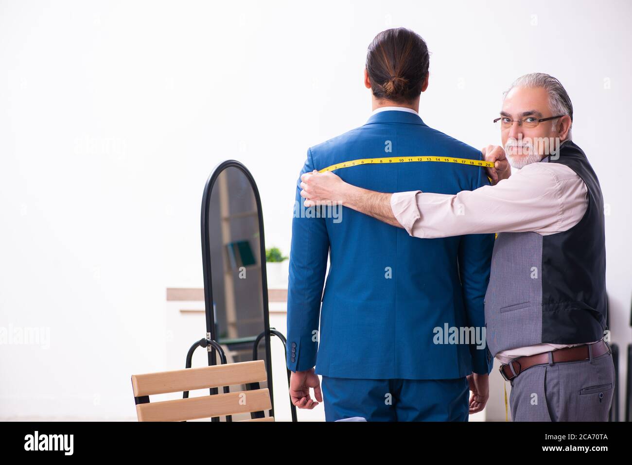 Young businessman visiting old tailor Stock Photo