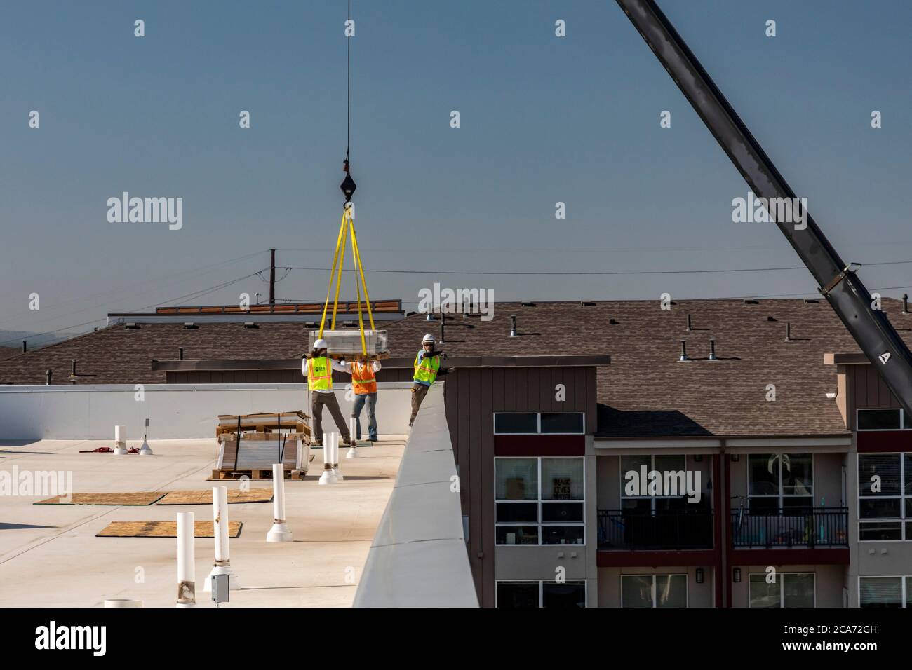 Denver, Colorado - Solar panels and other equipment for a solar energy installation are lifted to the top of a new affordable housing building. The so Stock Photo