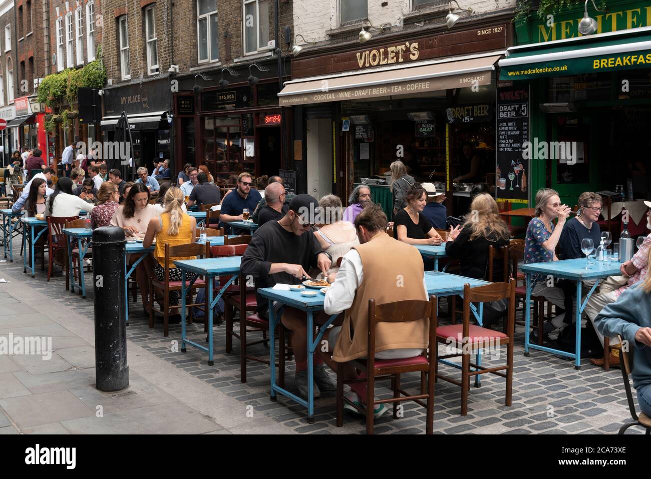 Diners eat food at outdoor restaurant tables in Soho during the Eat Out to Help Out scheme offering diners a discount off meals to help boost restaurants and pubs post-lockdown. Stock Photo