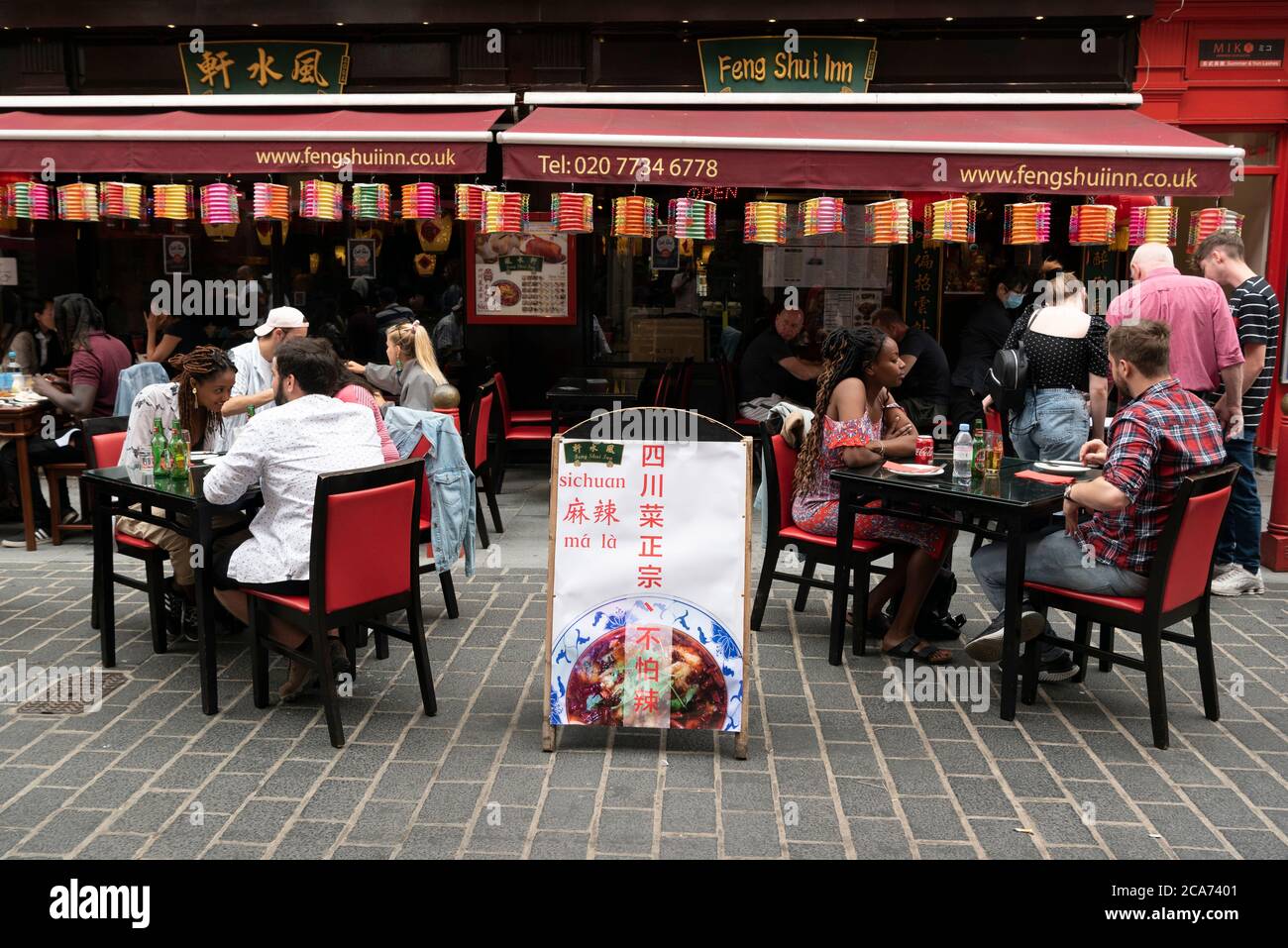 Diners eat food at outdoor restaurant tables in Chinatown during the Eat Out to Help Out scheme offering diners a discount off meals to help boost restaurants and pubs post-lockdown. Stock Photo