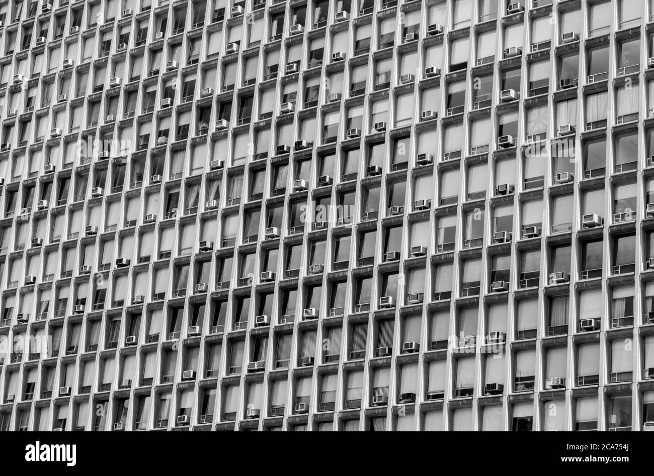 A towering New York building- each window holds a air conditioning unit in B&W (black and white) Stock Photo