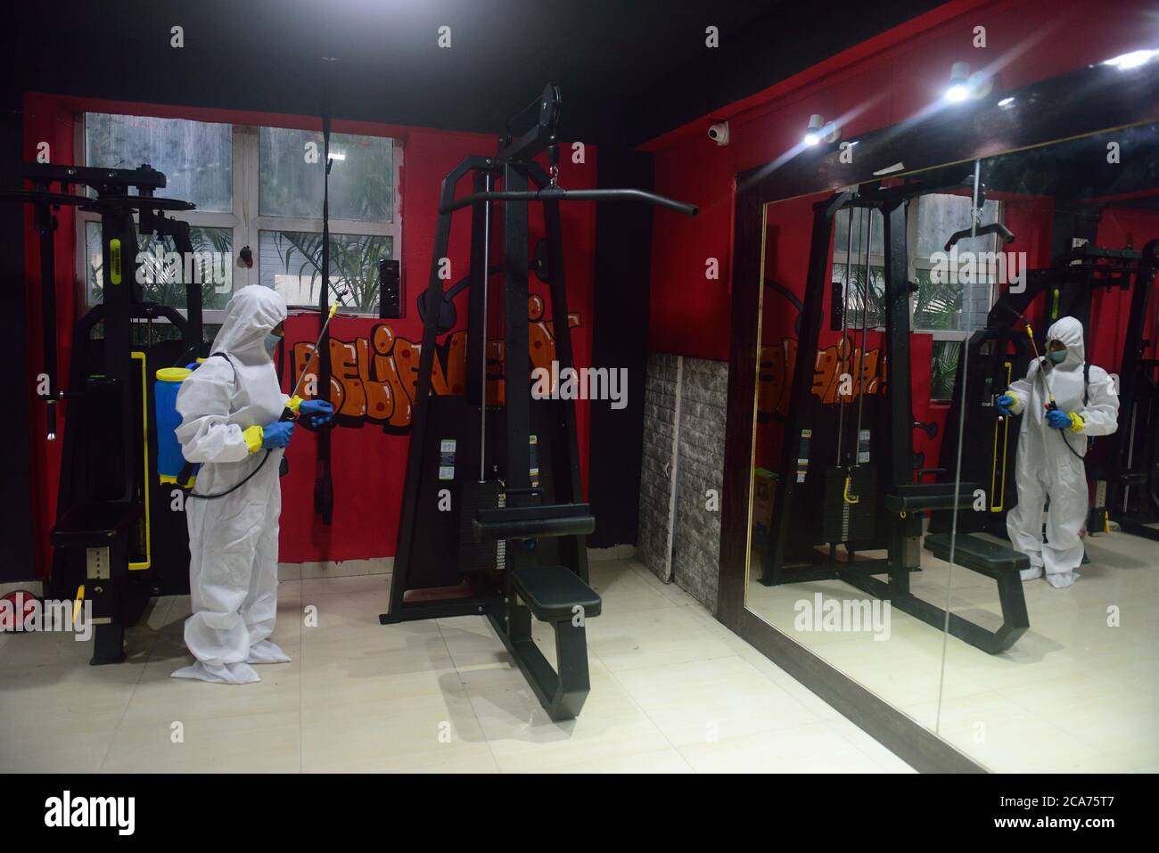 A worker wearing a personal protective equipment suit (PPE) sanitizes
