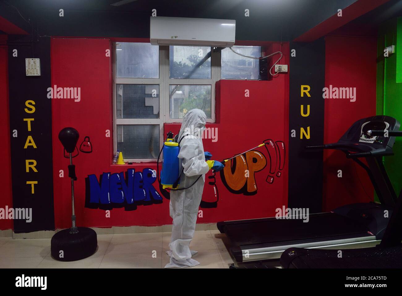 A worker wearing a personal protective equipment suit (PPE) sanitizes