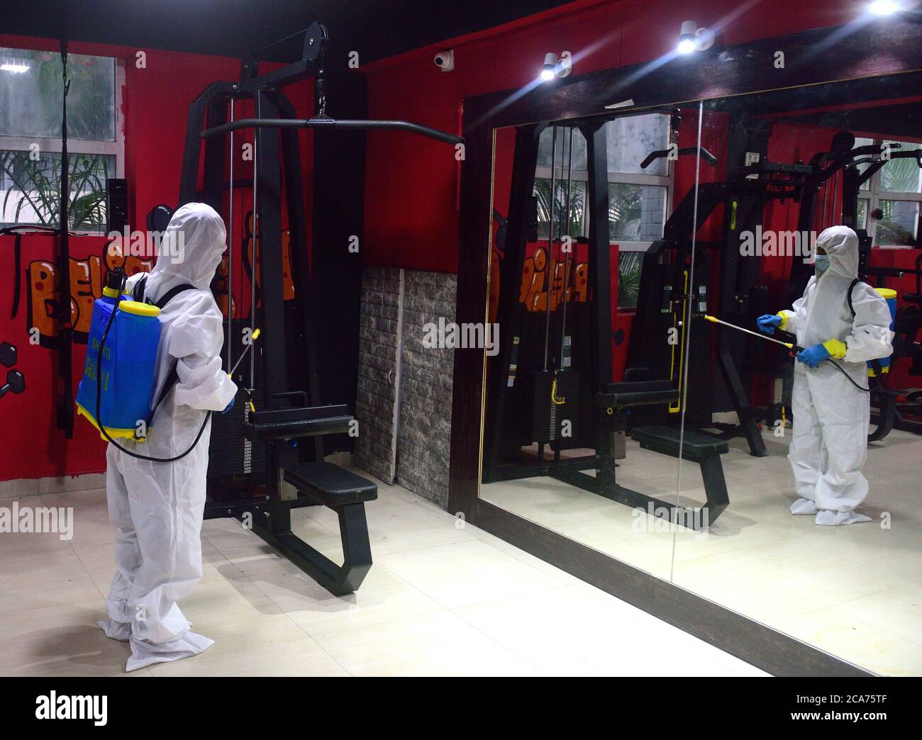 A worker wearing a personal protective equipment suit (PPE) sanitizes