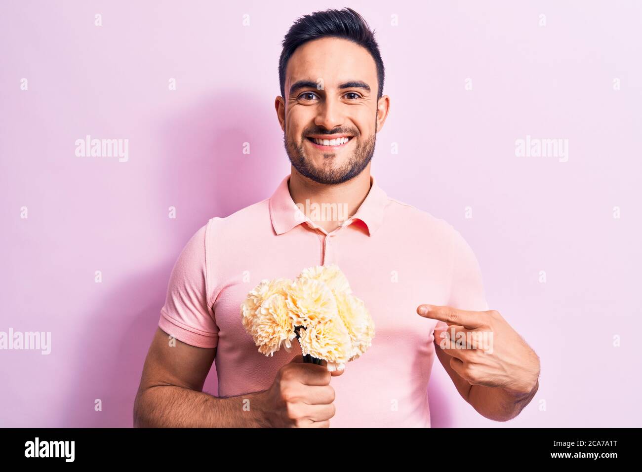 Young handsome romantic man with beard holding bouquet of flowers over ...