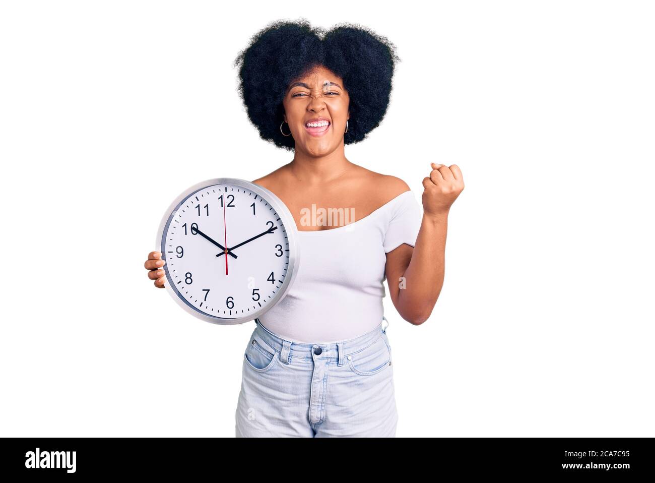 Young african american girl holding big clock screaming proud ...