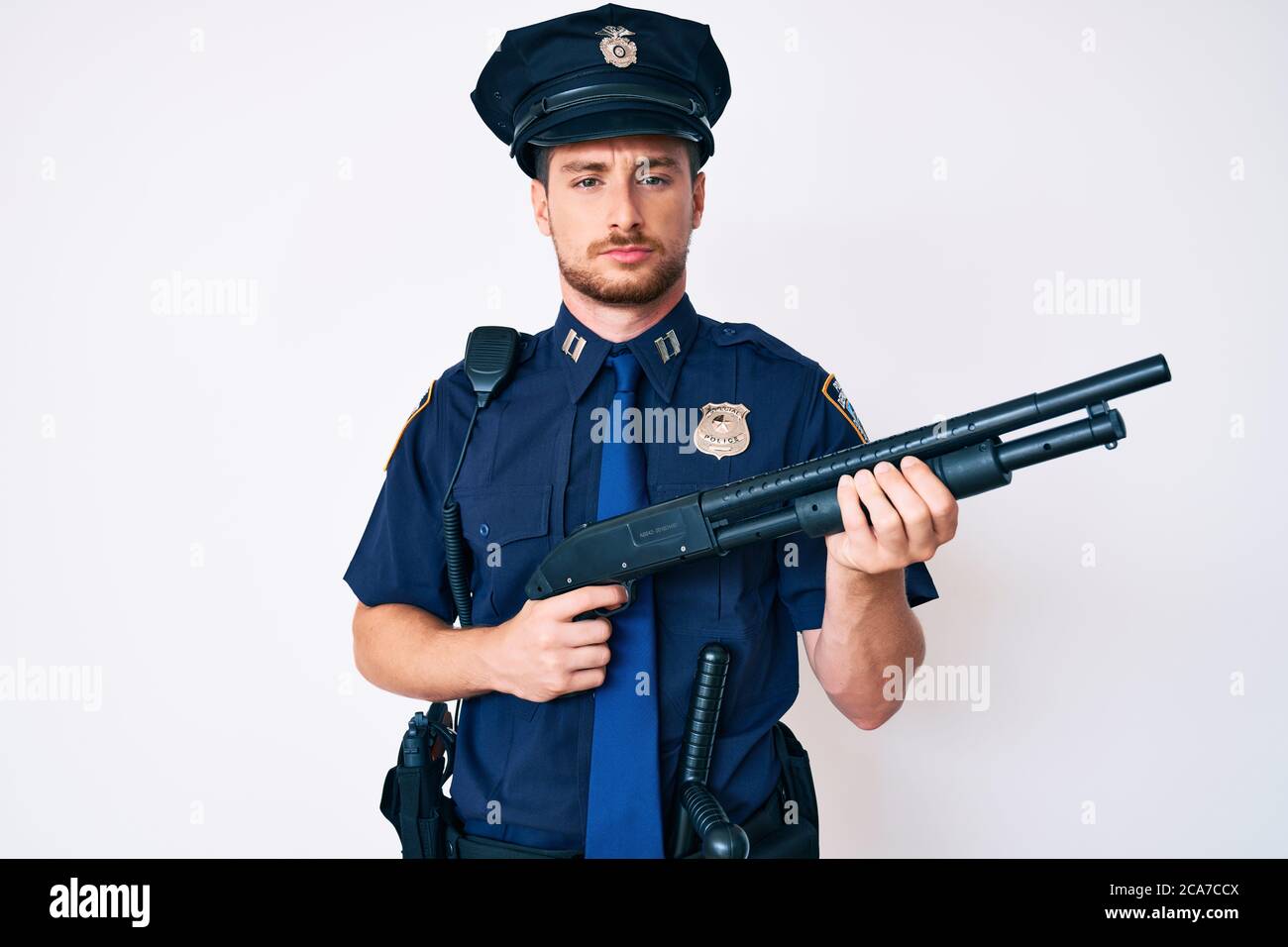 Young caucasian man wearing police uniform holding shotgun depressed and worry for distress, crying angry and afraid. sad expression. Stock Photo